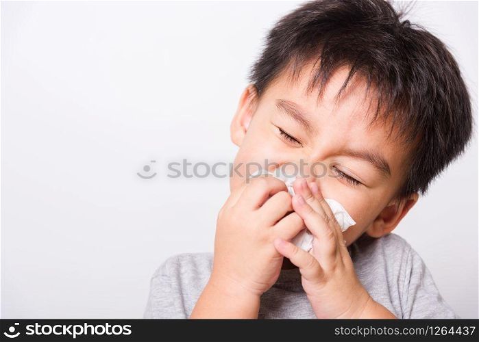 Closeup Asian face, Little children boy cleaning nose with tissue on white background with copy space, health medical care