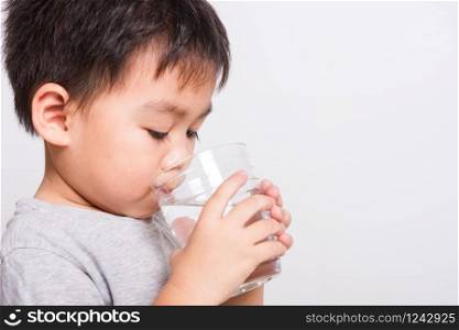 Closeup Asian face, Little children boy drinking water from glass on white background with copy space, health medical care