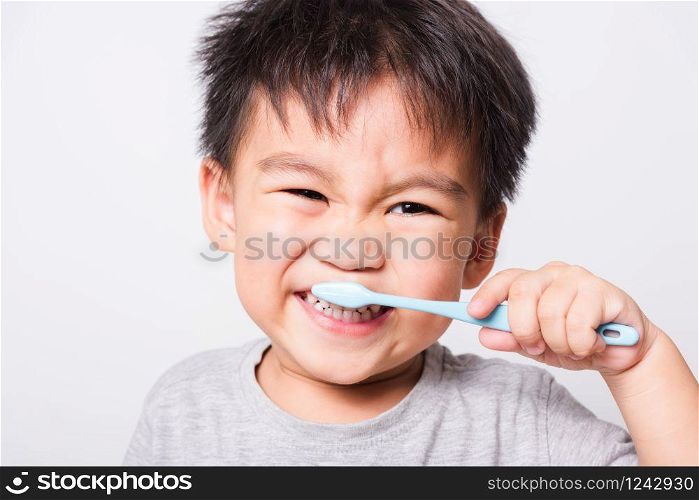 Closeup Asian face, Little children boy hand holds toothbrush he brushing teeth myself on white background with copy space, health medical care