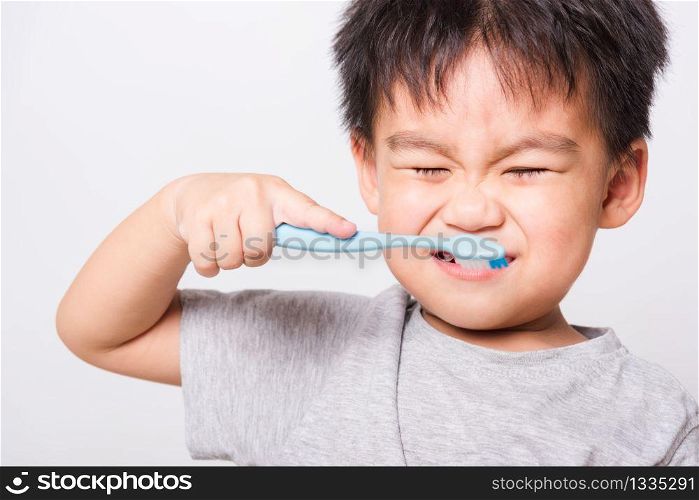 Closeup Asian face, Little children boy hand holds toothbrush he brushing teeth myself on white background with copy space, health medical care
