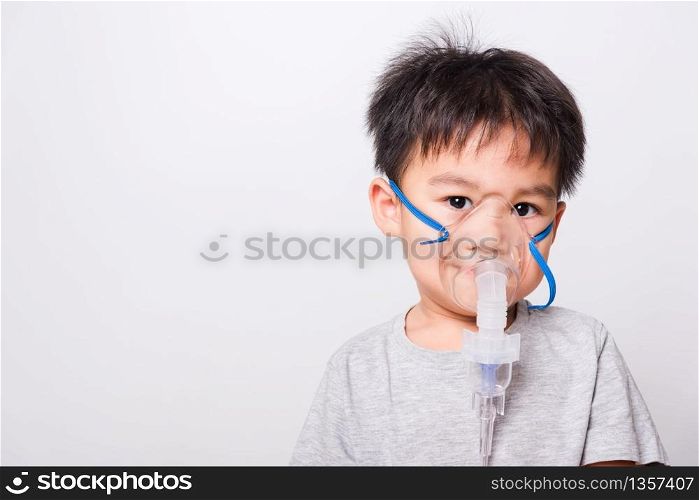 Closeup Asian face, Little children boy sick he using steam inhaler nebulizer mask inhalation oneself on white background, health medical care
