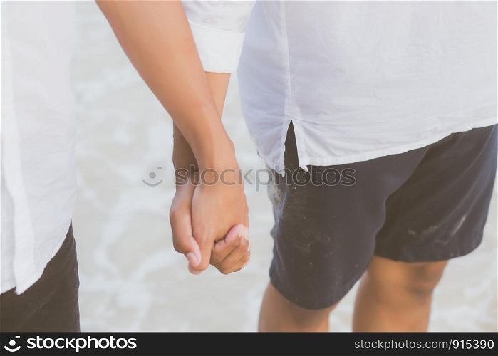 Closeup asian gay couple holding hands together on the beach with relax and leisure in summer, LGBT homosexual legal two man happy and romantic in vacation, relationship sex lover concept.