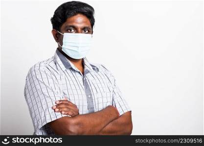 Closeup Asian handsome black man wearing surgical hygienic protective cloth face mask against coronavirus and stand crossed arm, studio shot isolated white background, COVID-19 medical concept