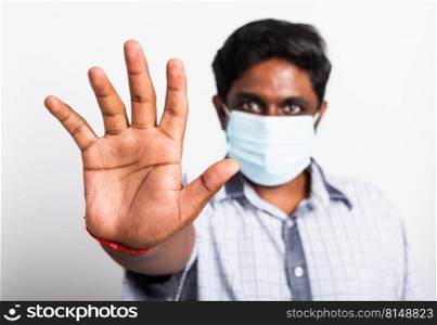 Closeup Asian handsome black man wearing surgical hygienic protective cloth face mask against coronavirus and raising hand stop sign, studio shot isolated white background, COVID-19 medical concept