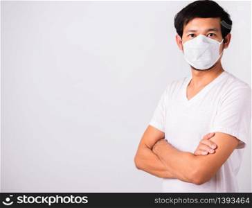 Closeup Asian handsome Man wearing surgical hygienic protective cloth face mask against coronavirus and stand crossed arm, studio shot isolated white background, COVID-19 medical concept