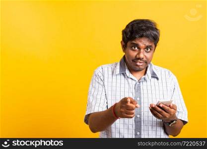 Closeup Asian happy portrait young black man holds a mobile smartphone and pointing finger out to the camera, studio isolated on yellow background