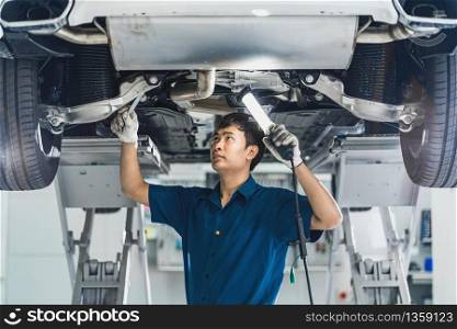 Closeup Asian mechanic hand repairing under the car in maintainance service center which is a part of showroom, technician or engineer professional work for customer, car repair and maintain concet