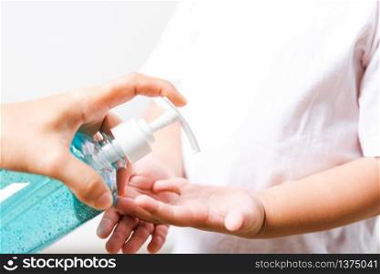 Closeup Asian Mother applying bottle pump dispenser sanitizer alcohol gel cleaning washing hands little child boy COVID-19 or coronavirus protection concept, isolated white background with copy space