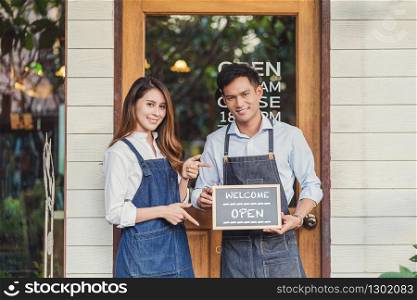 Closeup Asian partner Small business owner hands holding and showing the chalkboard with Welcome Open sign in front of coffee shop, startup with cafe store, installing open and close label concept