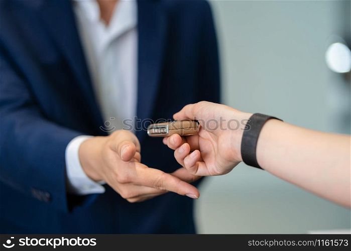 Closeup Asian receptionist hand recieving the automatic car key for checking at maintainance service center for in showroom