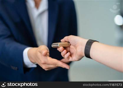 Closeup Asian receptionist hand recieving the automatic car key for checking at maintainance service center for in showroom