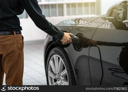 Closeup asian Technician hand is charging the electric car or EV in service center for maintainance, Eco-friendly alternative energy concept