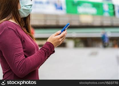 Closeup Asian woman hand using smart mobile phone with safety medical face mask for prevent Coronavirus or Covid19 Outbreak when travel to work in business downtown, Health care and infection concept