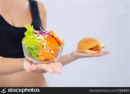 Closeup asian woman slim shape with diet choosing fresh salad vegetable and hamburger isolated on white background, food healthy with control for weight loss with calories, nutrition and lifestyle concept.