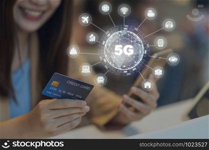 Closeup Asian woman using credit card by mobile for 5G technology with various icon internet of thing in department store, IOT and cashless concept, credit card mockup