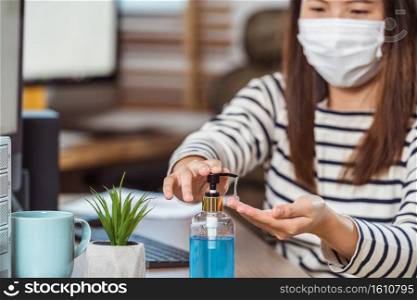 Closeup Asian woman worker hand sanitizer for cleaning her hand when working with computer in Home office when Covid-19 pandemic,Coronavirus outbreak,education and Social distancing,new normal concept