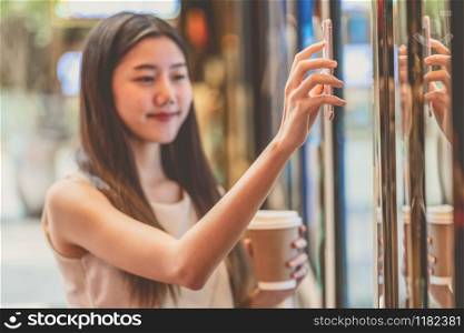 Closeup asian young woman hand using smart mobile phone scanning the movie tickets machine for buy and get the coupon in department store,lifestyle and leisure,entertain and technology scanner concept