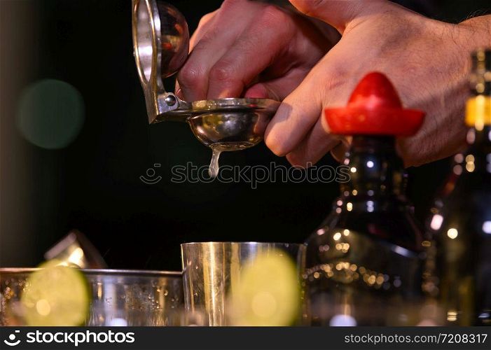 Closeup bartender hand preparing fresh juice cocktail in drinking wine glass with ice at night bar clubbing counter. Occupation and people lifestyles concept. Outdoor and nightclub background