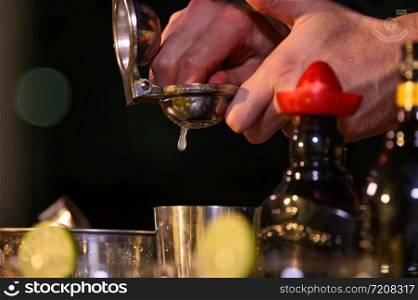 Closeup bartender hand preparing fresh juice cocktail in drinking wine glass with ice at night bar clubbing counter. Occupation and people lifestyles concept. Outdoor and nightclub background