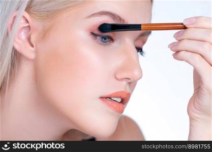 Closeup beautiful personable girl with flawless applying eye shadow makeup with eyeliner brush. Cosmetic facial painting process on lovely young woman with perfect clean skin in isolated background.. Closeup beautiful personable girl with flawless applying eye shadow makeup.