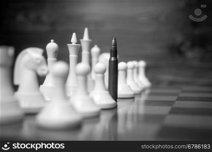 Closeup black and white conceptual photo of riffle bullet on chessboard