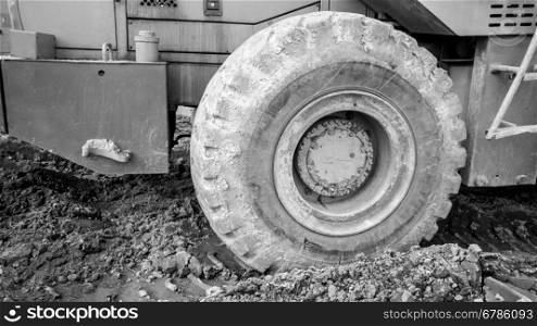 Closeup black and white photo of big excavator wheels on ground