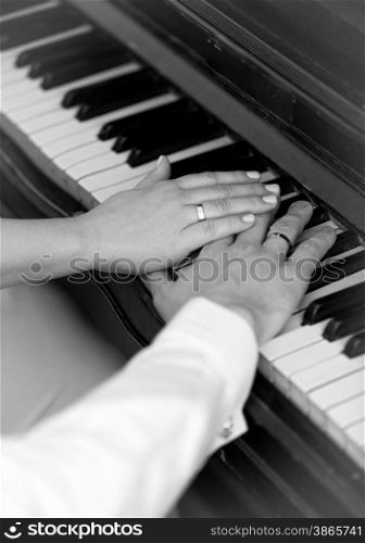 Closeup black and white photo of bride and groom playing on piano