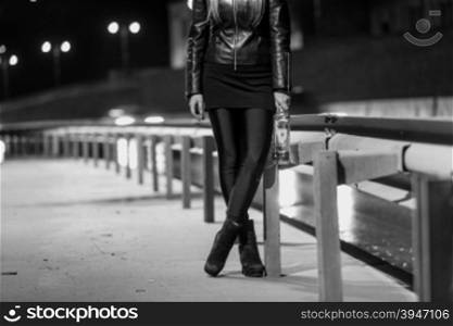 Closeup black and white photo of sexy woman walking by the road with bottle