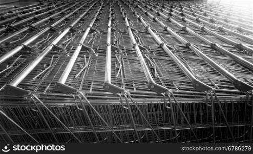 Closeup black and white photo of shopping carts in long rows