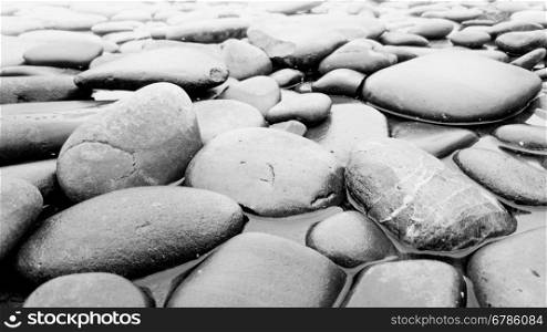 Closeup black and white photo of stones lying in river