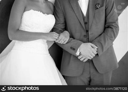 Closeup black and white photo of young bride holding grooms hand