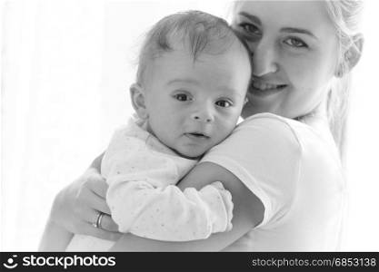 Closeup black and white portrait of beautiful young mother cuddling her adorable 3 months old baby boy