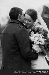 Closeup black and white portrait of handsome groom kissing bride in cheek