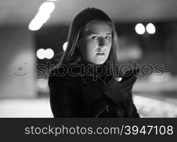 Closeup black and white portrait of lonely woman posing on dark street with telephone