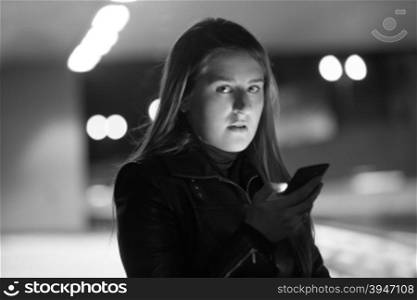 Closeup black and white portrait of lonely woman posing on dark street with telephone