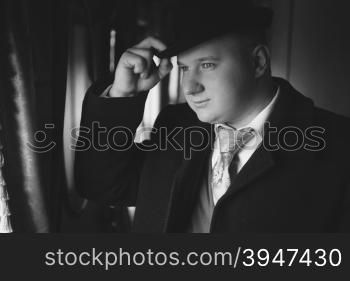 Closeup black and white portrait of man in bowler hat looking out train window