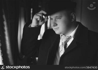 Closeup black and white portrait of man in bowler hat looking out train window