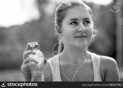 Closeup black and white portrait of sexy sporty woman with bottle of water at park