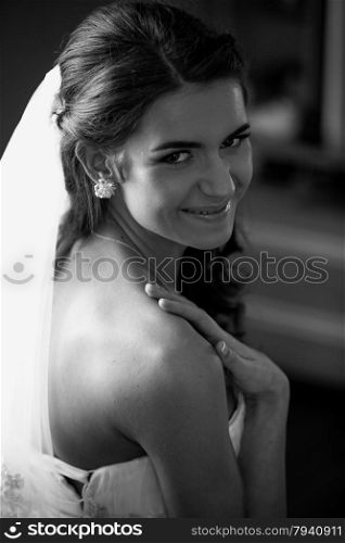 Closeup black and white portrait of smiling brunette bride with long white veil
