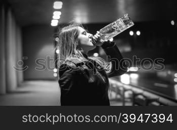 Closeup black and white portrait of woman drinking whiskey at night on street