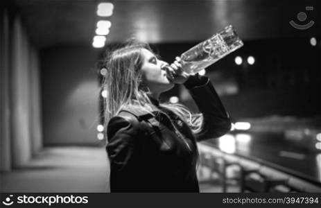 Closeup black and white portrait of woman drinking whiskey at night on street