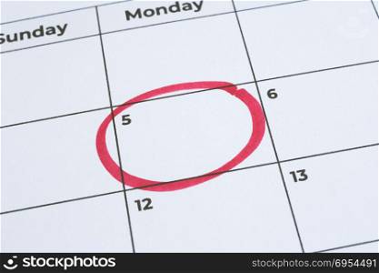 Closeup blank planner calendar, minimal style. Focus on the red circle mark on timetable date 5th. Important day, notification, reminder note, business timeline schedule, project management.