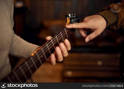 Closeup blurry hand of male musician playing guitar. Teacher and student at music lesson. Closeup hand of male musician playing guitar