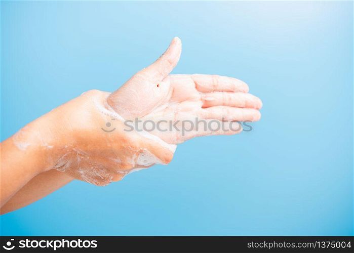 Closeup body care Asian young woman washing hands with soap have foam, hygiene prevention COVID-19 or coronavirus protection concept, isolated on blue background