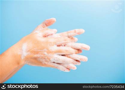 Closeup body care Asian young woman washing hands with soap have foam, hygiene prevention COVID-19 or coronavirus protection concept, isolated on blue background