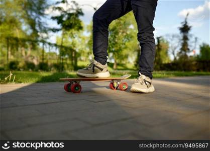 Closeup boy leg wearing trainers on skateboard over street background. Extreme skateboarding time on weekend. Closeup boy leg wearing trainers on skateboard over street background