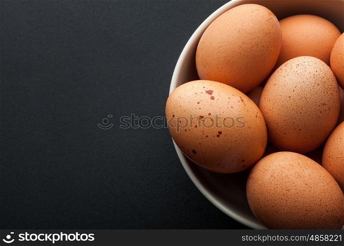 closeup brown eggs in bowl isolated on dark background