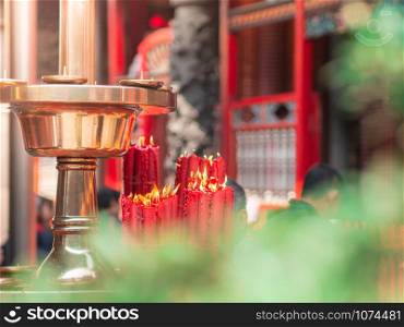 Closeup bundle of big red candles burning near the golden tray at Longshan temple, Taiwan.
