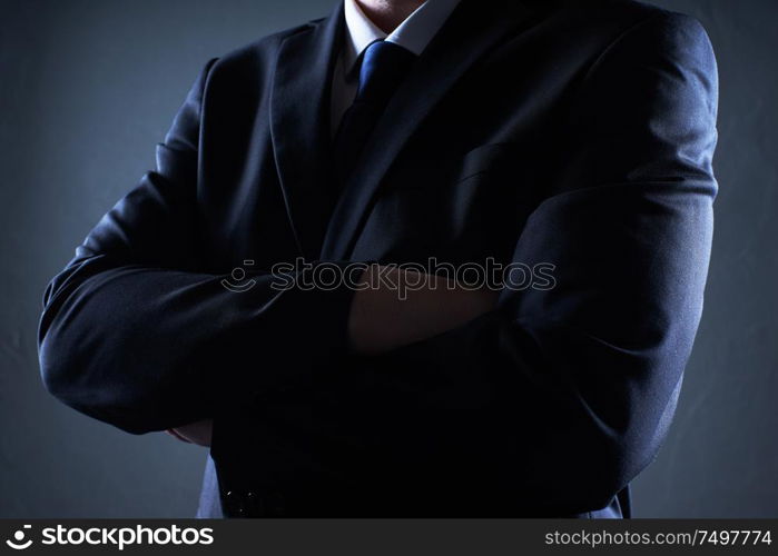 Closeup business man with crossed arms on black background