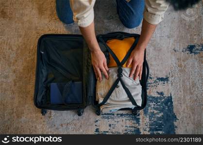 Closeup businessman hands and opened suitcase. Man packing clothes for business trip. Businessman packing clothes for trip crop shot